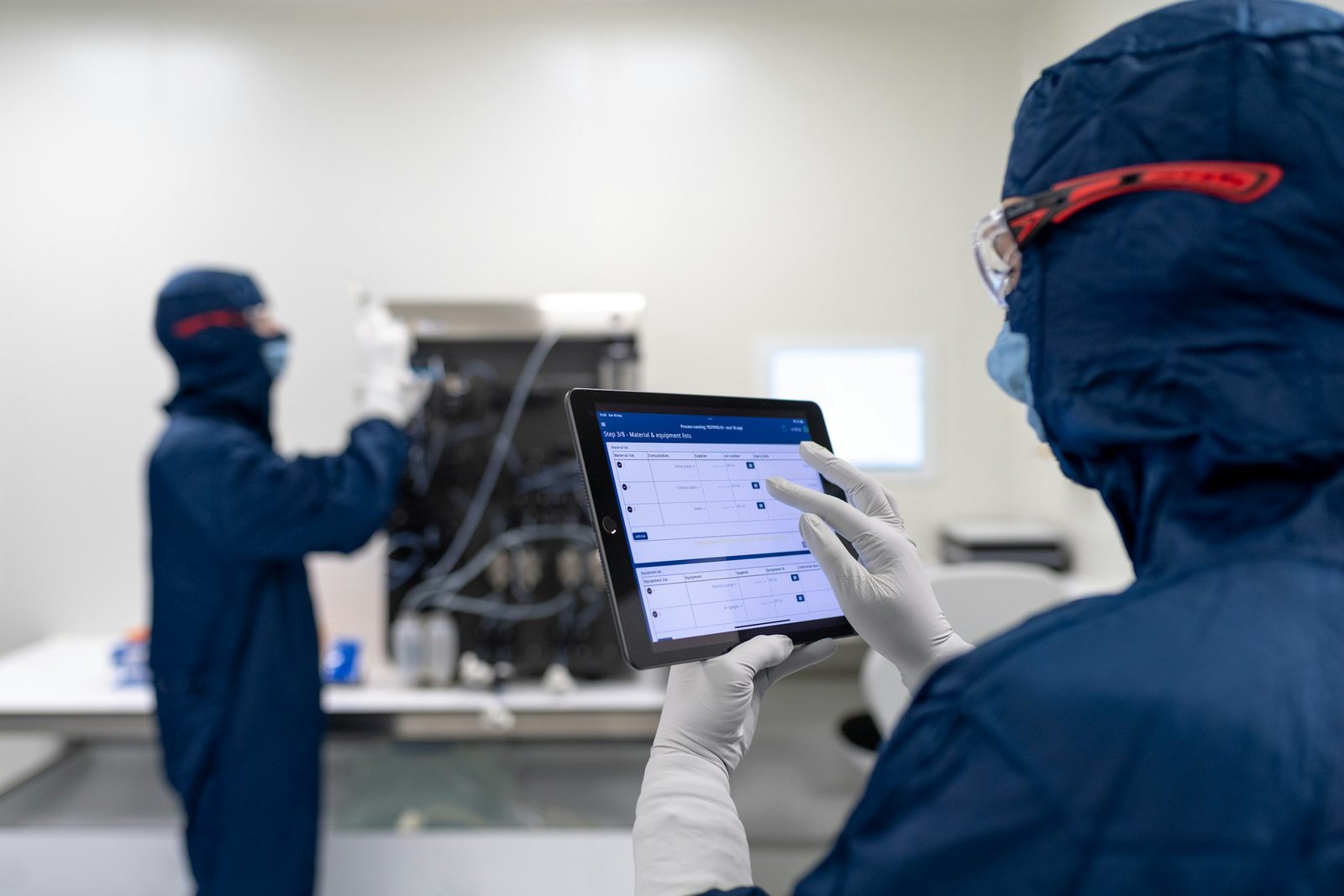 An engineer in a cleanroom reviewing results on a tablet