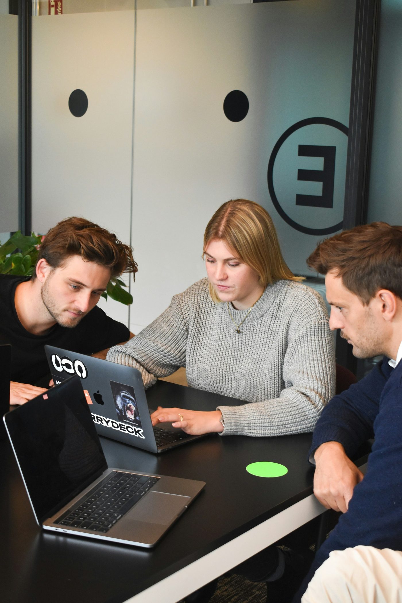 Three colleagues working together around a laptop